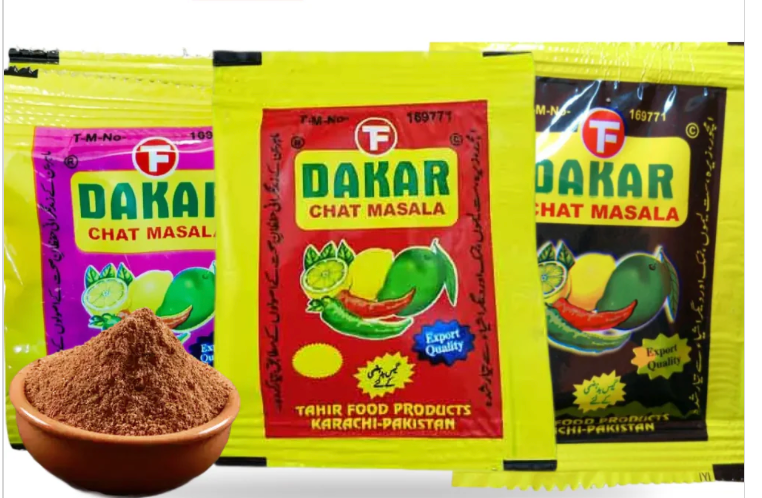 Three packages of Dakar Chat Masala with a bowl of spice in front